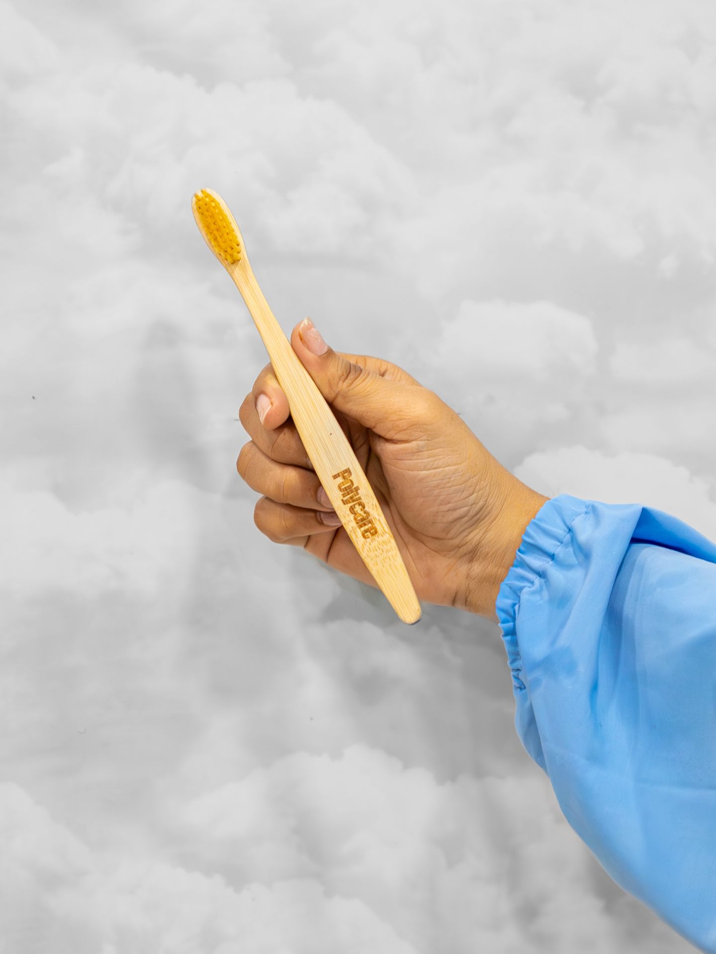 Hand holding a branded Polycare bamboo toothbrush